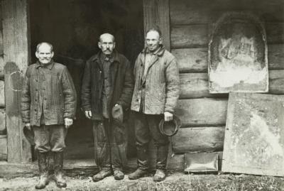 Older Men in Front of a Wooden Building — unknown
